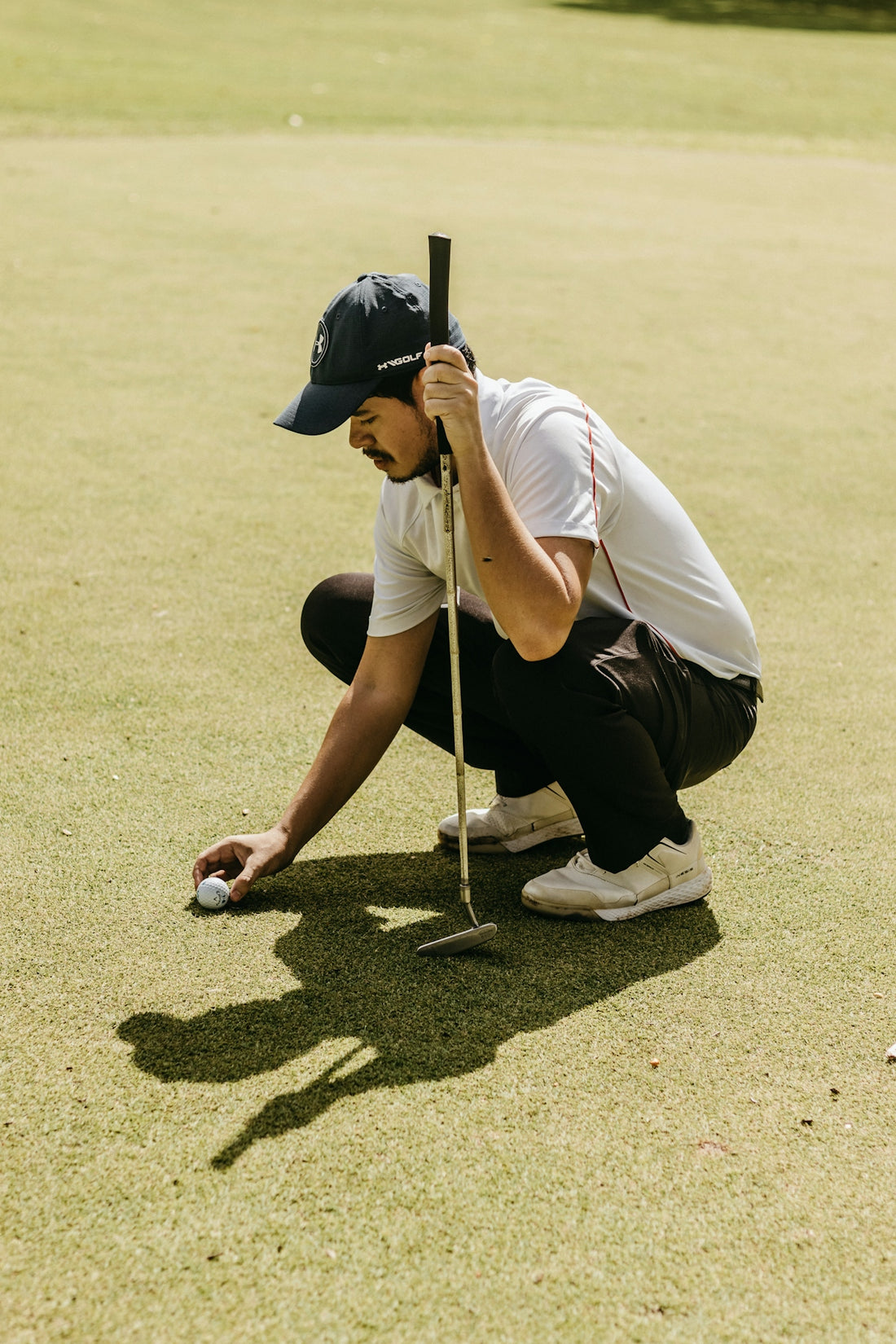 a man kneeling down on top of a green holding a golf club