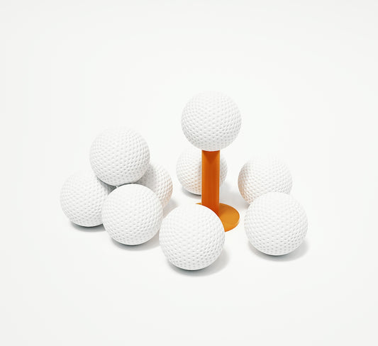 A group of white golf balls sitting on top of an orange tee