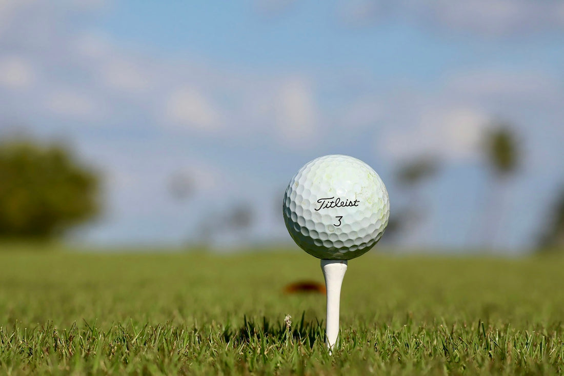 A golf ball sitting on top of a tee in the grass