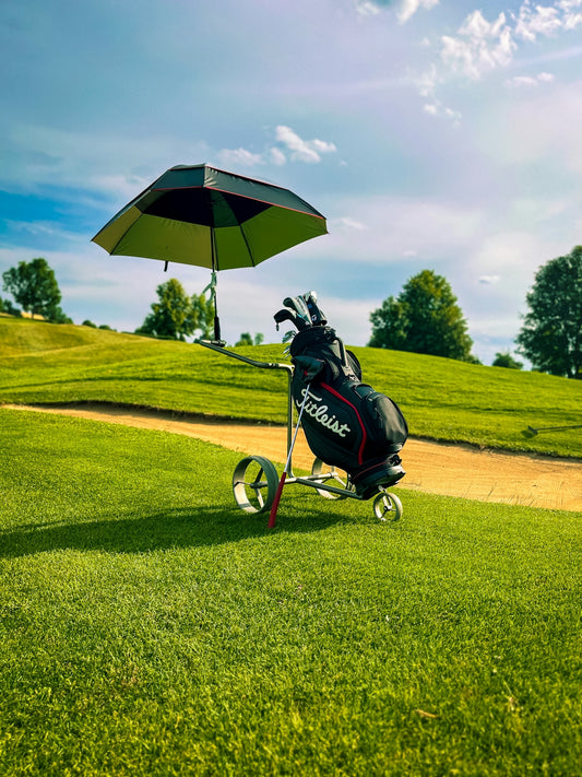 Golf bag with umbrella sits on a sunny golf course.