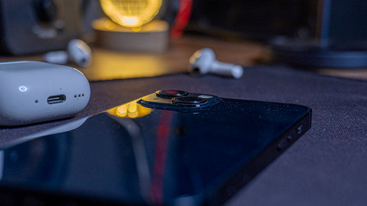 Smartphone, earbuds, and charging case arranged on a surface.