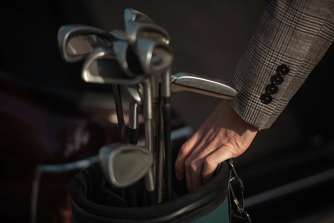 A man reaches for golf clubs.