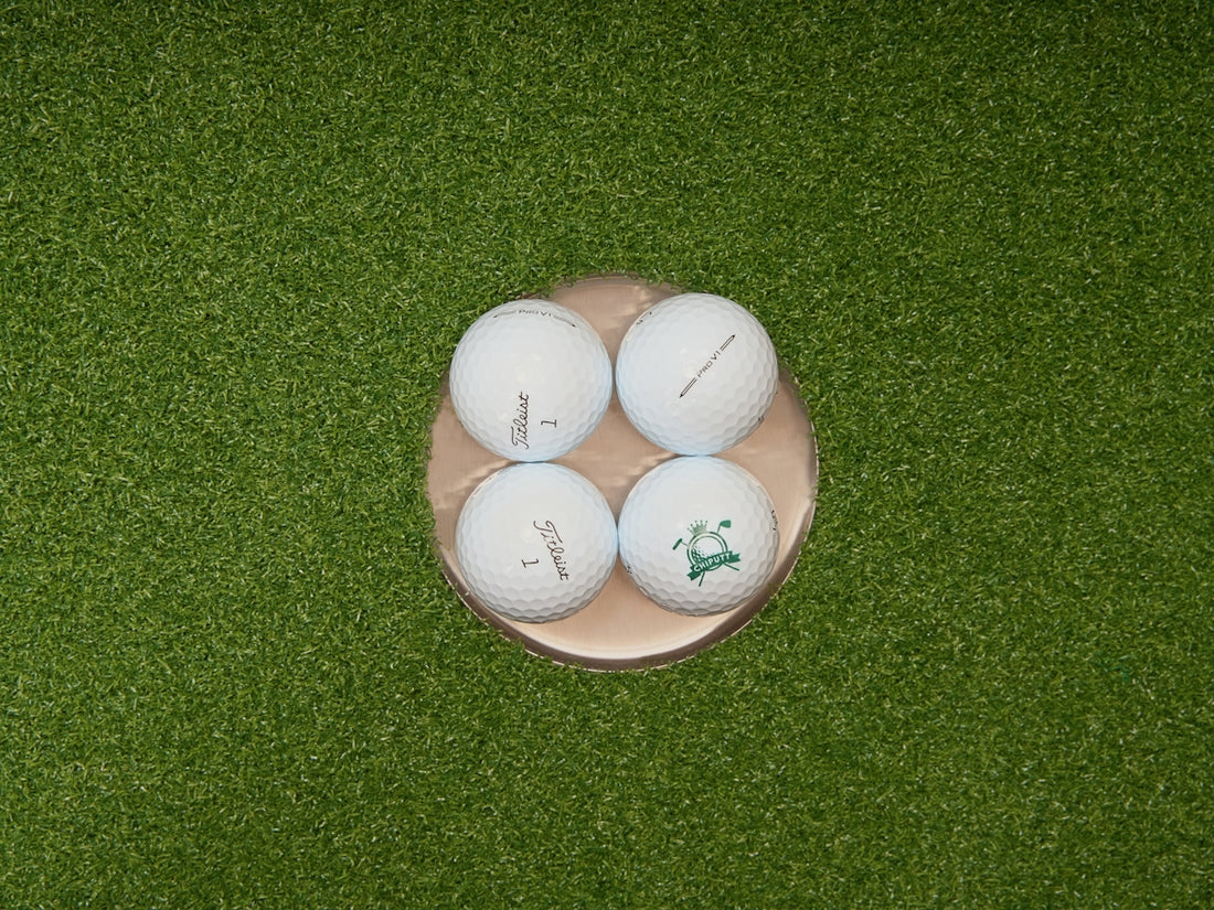 Four golf balls in a golf hole.