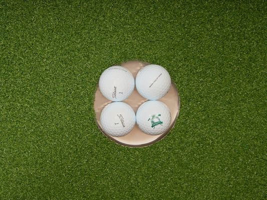 Four golf balls in a golf hole.