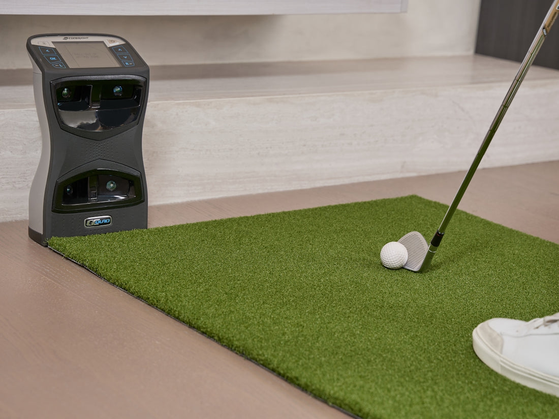 Golf club and ball on putting green with machine.