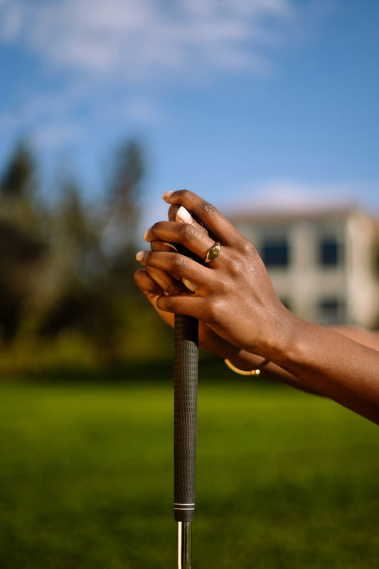 Hands gripping a golf club with a building in background