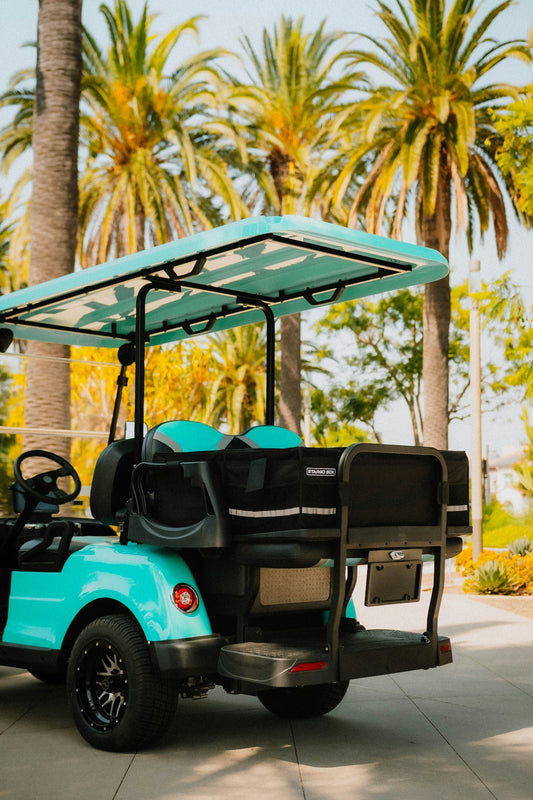 A turquoise golf cart parked outdoors with palm trees.
